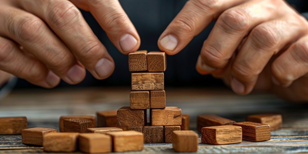 Businessman carefully protecting wooden blocks on table